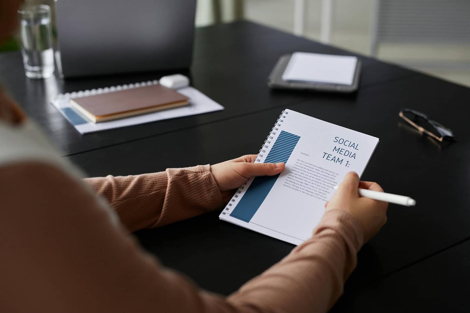 Close-up of an Affiliate Marketing  businesswoman holding a social media team notebook in a professional setting.